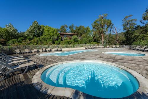 une piscine avec des chaises longues et 2 piscines dans l'établissement Camping Sole Di Sari, à Sari-Solenzara