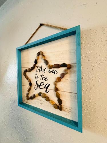 a picture of a sign that says like me to the sea at Brew You Bungalow - Cozy Oasis with Fire Pit in Dunedin