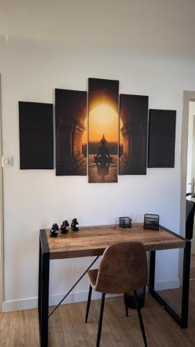 a room with a table and a wall with paintings at Maison cosy à Moyvillers classée de tourisme 3 étoiles in Moyvillers