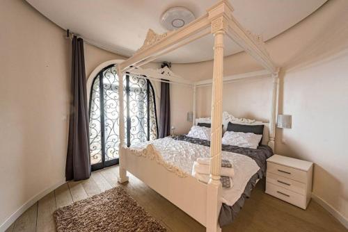 une chambre avec un lit à baldaquin et une fenêtre dans l'établissement Monaco Castle Villa with Pool and Skyview of French Riviera, à La Turbie