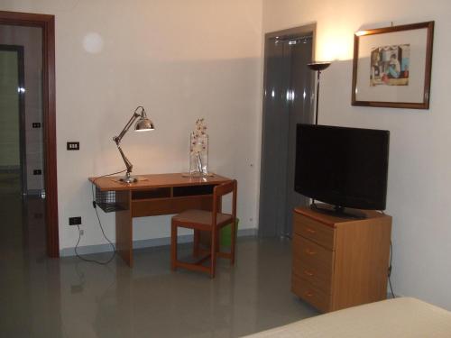 una camera da letto con scrivania, TV e lampada di Camere Mazara a Mazara del Vallo