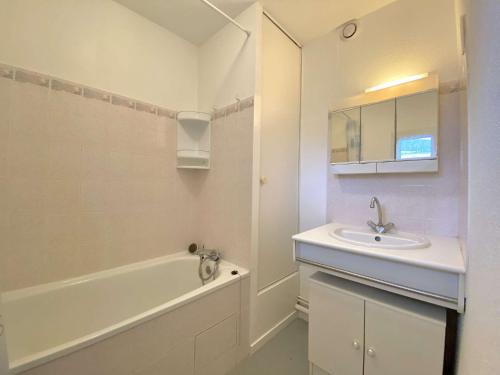 La salle de bains blanche est pourvue d'un lavabo et d'une baignoire. dans l'établissement REF 042 Appartement T2 avec balcon et piscine Arzon, à Arzon
