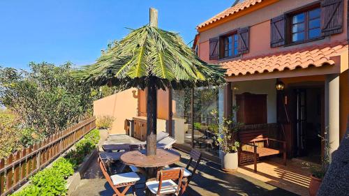a patio with a table and a umbrella on a house at Refúgio da Ribeira in Porto Moniz