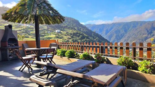 a patio with a table and chairs and an umbrella at Refúgio da Ribeira in Porto Moniz