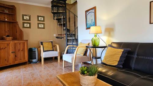 a living room with a leather couch and chairs at Refúgio da Ribeira in Porto Moniz