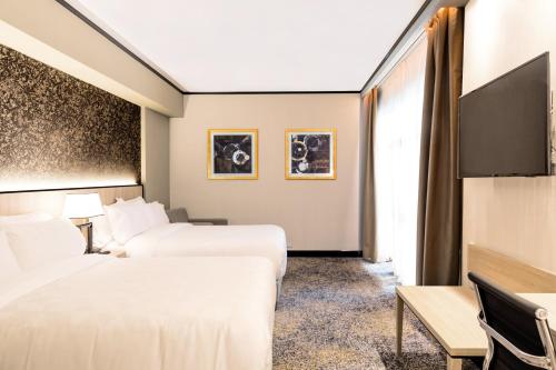 a hotel room with two beds and a flat screen tv at Holiday Inn Rosario by IHG in Rosario