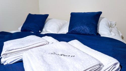 a bed with blue sheets and white towels on it at Przy Teatrze by LibertaRent in Wałbrzych