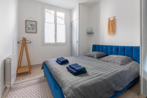 une chambre avec un lit bleu avec deux serviettes dessus dans l'établissement Le Nossa - Centre - Proche Halles, à Lourdes