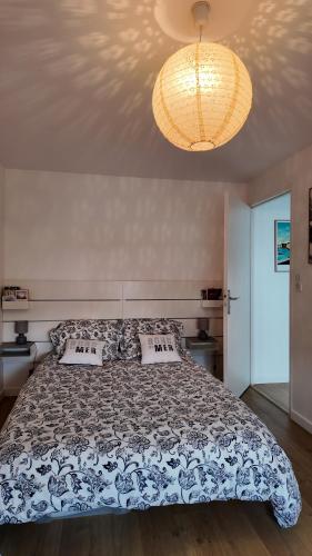 une chambre avec un lit et un lustre dans l'établissement **La Bretonnerie, bel appartement de standing, à Concarneau