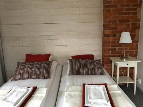 two beds in a room with a table and a lamp at Ödevata Gårdshotell in Emmaboda