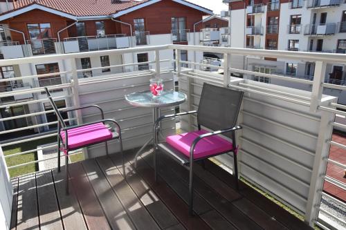 a balcony with pink chairs and a table on a building at Gdansk Neptun Park apartament 4 osobowy przy plaży in Jelitkowo