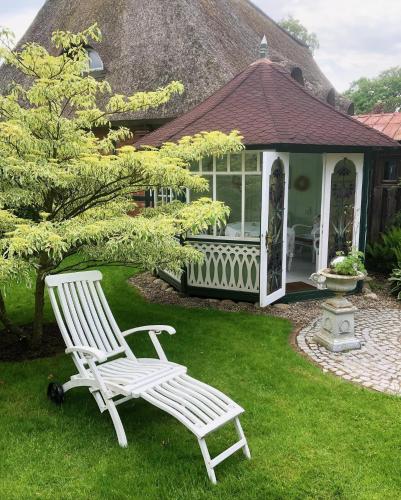 two white chairs sitting in the grass in front of a house at Landhaus Hüttblek in Hüttblek