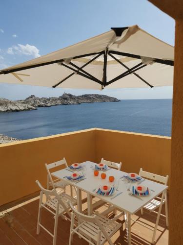une table et des chaises sur un balcon avec vue sur l'océan dans l'établissement ILE du FRIOUL féérique 102m2 8p superbe appartement VUE MER 3 terrasses plage à pied, à Marseille