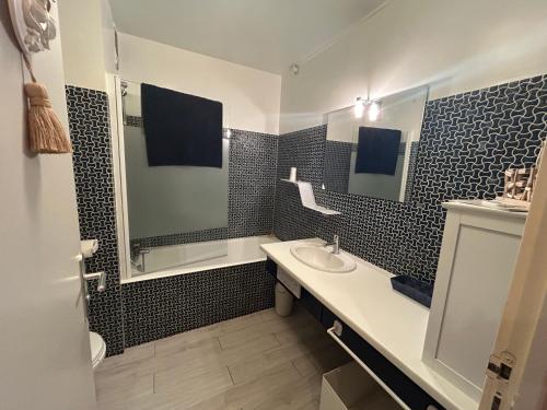 une salle de bain en noir et blanc avec un lavabo et un miroir dans l'établissement Studio-Cabine PLEINE VUE MER ET EVENTAIL CABOURG, à Cabourg