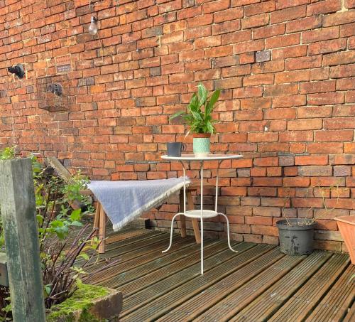 a table with a potted plant sitting next to a brick wall at Old country cottage in Ashbourne