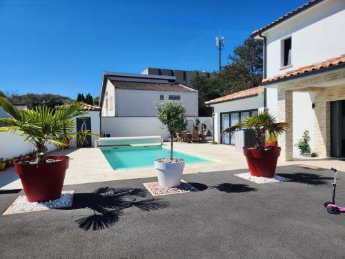 une cour arrière avec des plantes en pot et une piscine dans l'établissement Villa avec piscine jacuzzi et sauna, à Saint-André-de-Cubzac