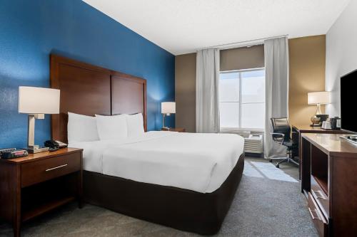 a bedroom with a large bed and a blue wall at Comfort Inn & Suites near Tinley Park Amphitheater in Tinley Park