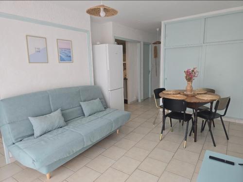 un salon avec un canapé bleu et une table dans l'établissement Plage des Chalets appartement T2+terrasse, à Gruissan