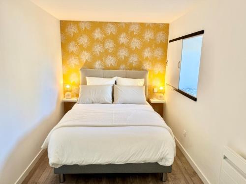 une chambre avec un lit avec des draps blancs et une fenêtre dans l'établissement Ty Juline - Bord de mer et chemin de randonnée GR34, à Guissény