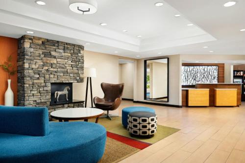 a lobby with a fireplace and a blue couch and chair at Fairfield Inn Concord in Concord