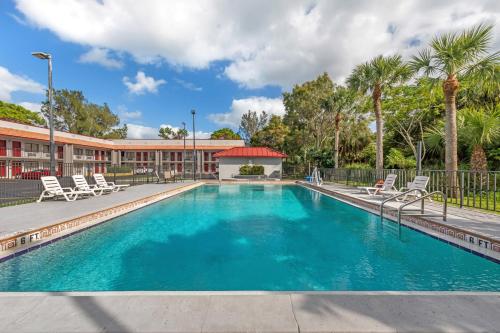 a swimming pool with chairs and a building at Red Roof Inn Ft Pierce in Fort Pierce