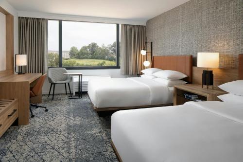 a hotel room with two beds and a desk at Sheraton Westport Plaza in Maryland Heights