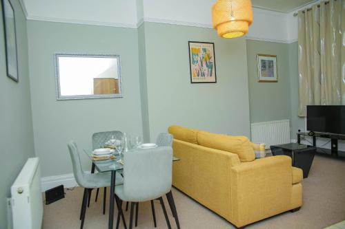 a living room with a yellow couch and a table at Elms West Court in Sunderland