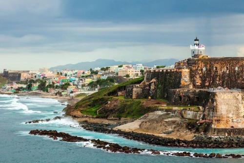 a lighthouse on top of a cliff next to the ocean at 2BR- Villa D'Oro at Villas Playa I in Dorado