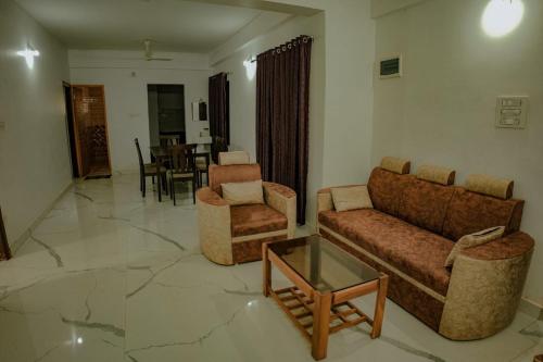 a living room with couches and chairs and a table at Shri Devi Mookambika - Apart Hotel in Kollūru