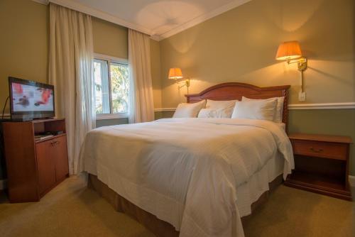 - une chambre avec un grand lit et une télévision dans l'établissement Hotel Villa Morra Residence, à Asuncion