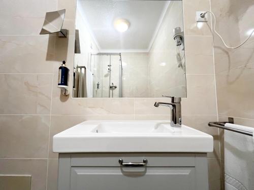 a bathroom with a white sink and a shower at Quartos da Vila - Duna Parque Resorts & Hotels in Vila Nova de Milfontes