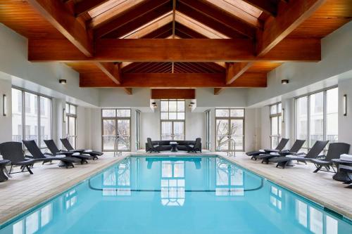 an indoor pool with chairs and a ceiling with beams at Detroit Metro Airport Marriott in Romulus