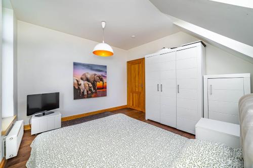 a white bedroom with a bed and a flat screen tv at Amber Villa in Rīga