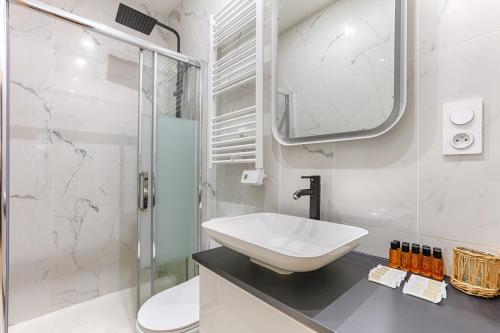 une salle de bain blanche avec un lavabo et une douche dans l'établissement Paris Montmartre Sacré Cœur Superb Duplex, à Paris