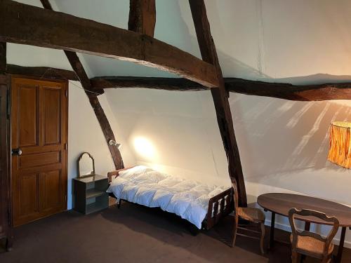 - une chambre avec un lit, une table et une porte dans l'établissement Chaumière normande, les pommiers proches de la mer, à Blonville-sur-Mer