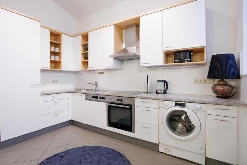 a kitchen with white cabinets and a washing machine at Belvedere City Apartment in Vienna