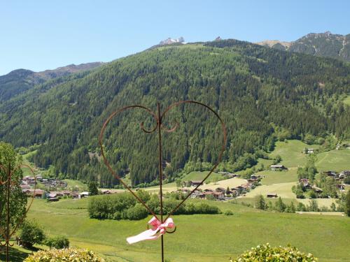 a metal heart sculpture in a field with a mountain at Alpenferienwohnung Strickner in Neustift im Stubaital