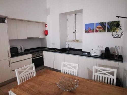 een keuken met witte kasten en een houten tafel bij Casa da Vila in Ferragudo