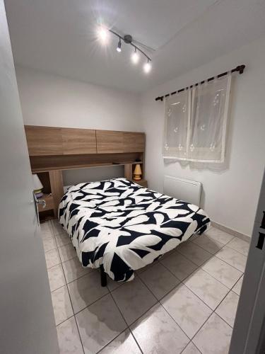 una camera da letto con un letto con un piumone bianco e nero di Appartement à ARGELES SUR MER PLAGE ad Argelès-sur-Mer