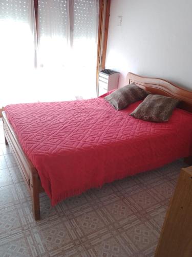 a bed with a red comforter and pillows in a bedroom at Casa en la costa in Necochea