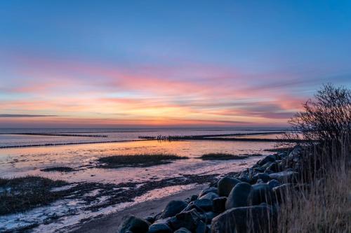 a sunset over a beach with rocks and the ocean at Boutiquehotel Seiler Hof Keitum in Keitum