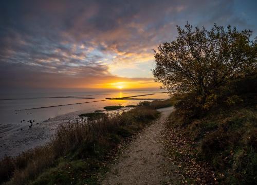 a dirt road next to the ocean at sunset at Boutiquehotel Seiler Hof Keitum in Keitum