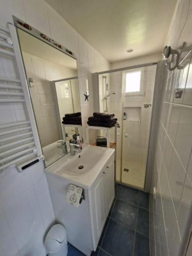 une salle de bain blanche avec un lavabo et un miroir dans l'établissement Albizia, à Saint-Pair-sur-Mer