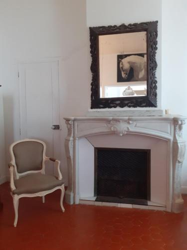 Cette chambre dispose d'une cheminée avec un miroir et une chaise. dans l'établissement Grande chambre avec parties communes en bord de mer, à Port-la-Nouvelle