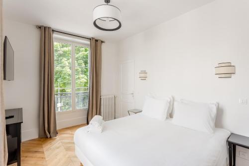 une chambre avec un grand lit blanc et une fenêtre dans l'établissement The black Swan, à Paris
