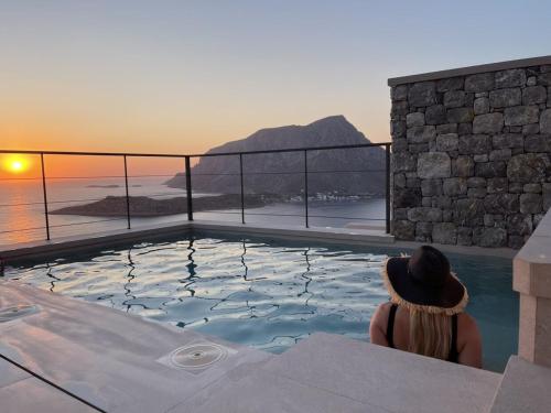 a woman sitting in a pool watching the sunset at Gestema Luxury Residences in Kalymnos
