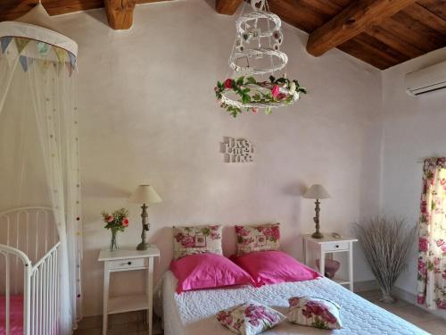 - une chambre avec un lit doté d'oreillers roses et d'un lustre dans l'établissement Le Mas Joyeux - L'Olivier - Gîte En Cévennes, à Saint-Florent-sur-Auzonnet