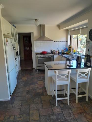 a kitchen with a refrigerator and a table and chairs at Red Kennel Budget Private Rooms - Trott Park in Happy Valley