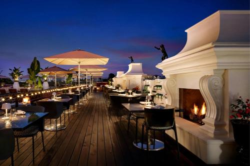 a restaurant with tables and a fireplace on a deck at night at SLS Hotel, a Luxury Collection Hotel, Beverly Hills in Los Angeles