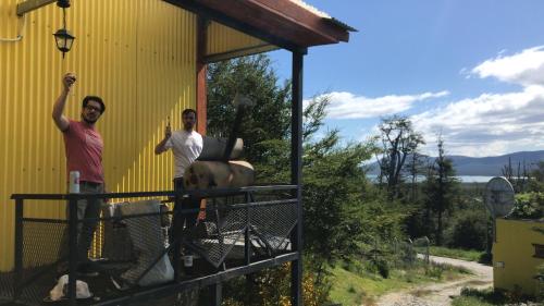 two men are standing next to a yellow building at Cabaña de las Flores in Tolhuin